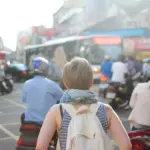 Solo traveler with a backpack walking through a busy city square