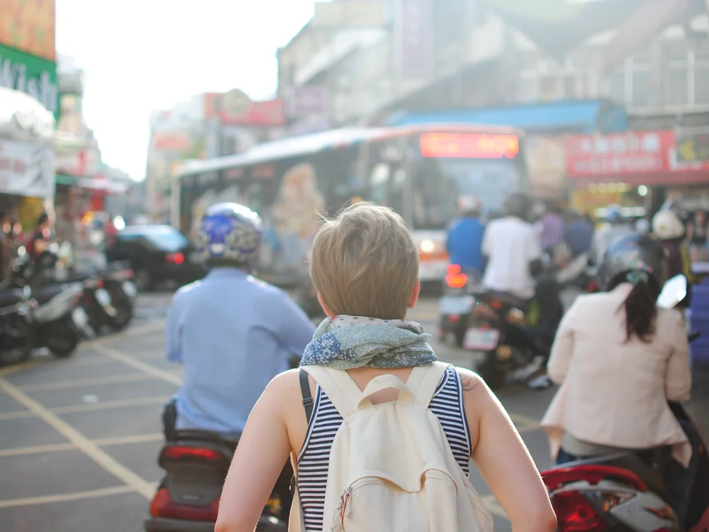 Solo traveler with a backpack walking through a busy city square